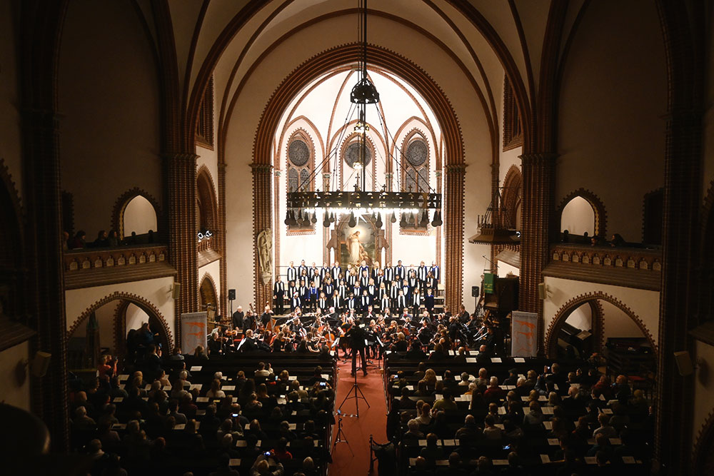 Gesamtansicht des Kirchenschiffes innen mit Zuschauern, Chor und Orchester