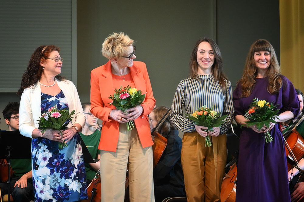 Die vier Fachgruppenleiterinnen stehen fröhlich mit Blumen in der Hand auf der Bühne