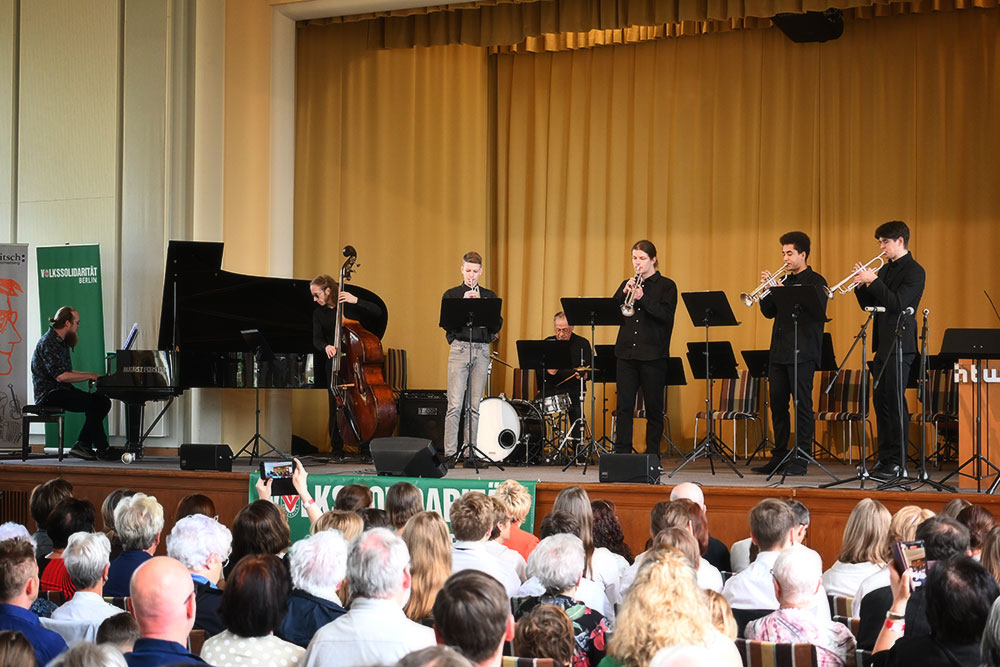 Ein Ensemble - bestehend aus einem Pianisten, einem Bassisten, vier Trompetern und einem Schlagzeuger spielt auf der Bühne vor dem Publikum